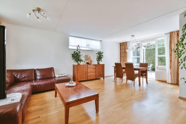 Günümüz minimalist tasarımı. Hafif stüdyo dairesinin ahşap masası ve oturma odası ile beyaz duvarları ve parke zemini arasında yemek masası ve sandalyeleri var.