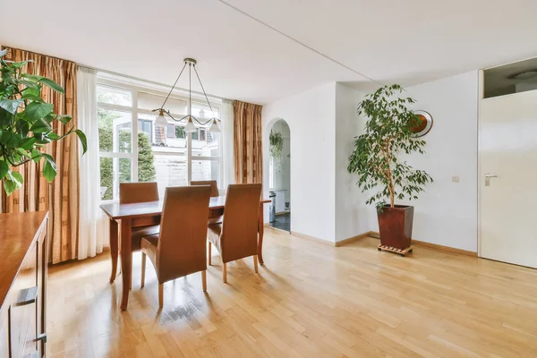 Günümüz minimalist tasarımı. Hafif stüdyo dairesinin ahşap masası ve oturma odası ile beyaz duvarları ve parke zemini arasında yemek masası ve sandalyeleri var.