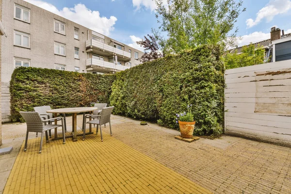 Oturma alanı ve ahşap çitlerin yanındaki küçük bahçesi olan düzgün asfaltlı bir avlu.