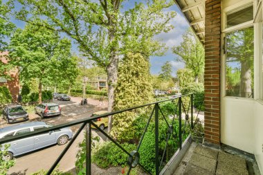 Panoramic view of brick buildings with parking and trees from small balcony