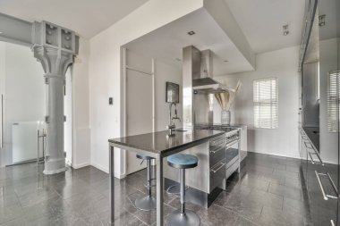 Çağdaş dairenin geniş odasındaki dinlenme odası ve mutfağın yakınındaki sandalyeli ve çiçekli masa.