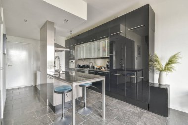 Çağdaş dairenin geniş odasındaki dinlenme odası ve mutfağın yakınındaki sandalyeli ve çiçekli masa.