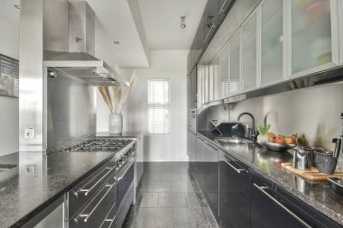 Çağdaş dairenin geniş odasındaki dinlenme odası ve mutfağın yakınındaki sandalyeli ve çiçekli masa.