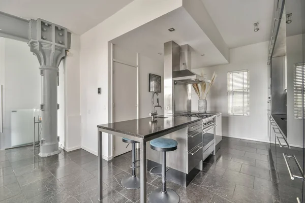 Çağdaş dairenin geniş odasındaki dinlenme odası ve mutfağın yakınındaki sandalyeli ve çiçekli masa.