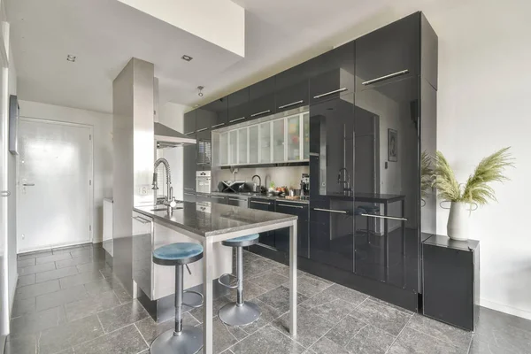 Çağdaş dairenin geniş odasındaki dinlenme odası ve mutfağın yakınındaki sandalyeli ve çiçekli masa.