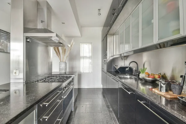 Çağdaş dairenin geniş odasındaki dinlenme odası ve mutfağın yakınındaki sandalyeli ve çiçekli masa.