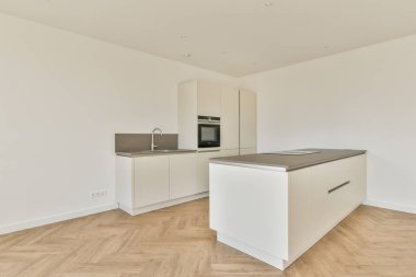 Pencereleri ve ahşap parke zemini olan boş beyaz mutfağın içi.