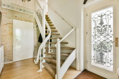 Beyaz spiral merdiven, çağdaş evi ahşap zemin ve beyaz duvarlarla birbirine bağlıyor.