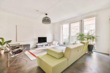 Yastıkları olan rahat bir kanepe. Duvara yaslanmış TV ve dekorasyonlar modern sevgi odasında.