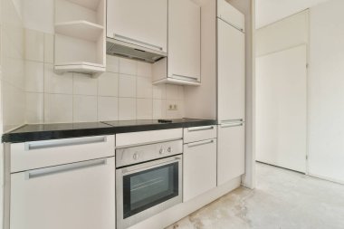 Pencereleri ve ahşap parke zemini olan boş beyaz mutfağın içi.