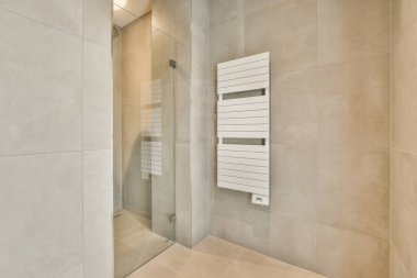 Evdeki modern tuvalette asılı duran banyo musluğu ile duvar arasındaki cam bölme.