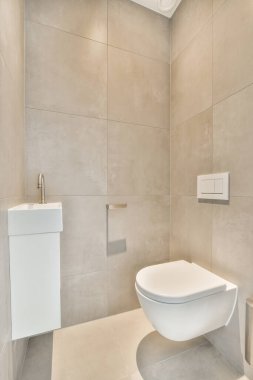 Evdeki modern tuvalette asılı duran banyo musluğu ile duvar arasındaki cam bölme.