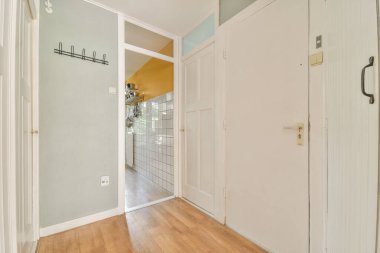 Beyaz duvarları ve aynalı gardırobu ve minimalist tarzda parke zemini olan boş dar koridor manzarası.