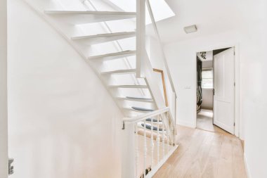 Çerçevelenmiş resimlerin yanındaki beyaz oda kapısı ve evdeki merdivenlerin üstündeki şık lamba.