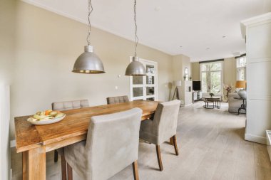 Modern apartmandaki dekorasyonlu ve televizyonlu, rahat koltuğun yanına yerleştirilmiş eski püskü ahşap masa.