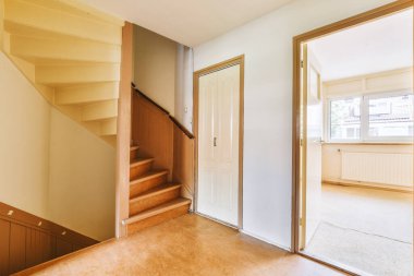 Minimalist iç tasarımı olan modern lüks dairenin ikinci katına çıkan ahşap merdivenli beyaz koridor.