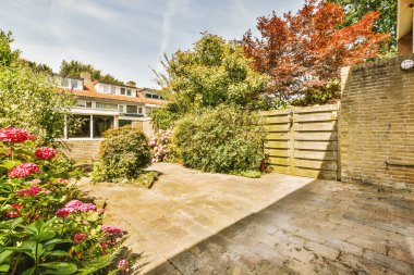 Oturma alanı ve ahşap çitlerin yanındaki küçük bahçesi olan düzgün asfaltlı bir avlu.