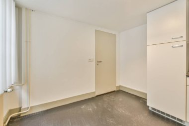 Pencereleri ve ahşap parke zemini olan boş beyaz mutfağın içi.