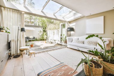 Rahat koltuklar ve ahşap masa modern dairenin oturma odasının penceresinin yanındaki saksı bitkilerinin yanına yerleştirildi.