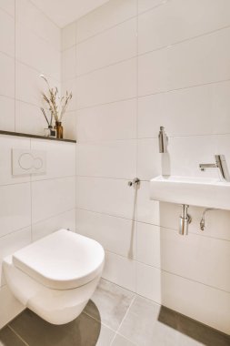 Lavabolu ve duvarlı, beyaz duvarlı ve kareli tuvaletli dar bir tuvalet.