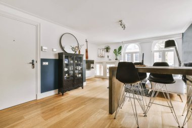 Günümüz minimalist tasarımı. Hafif stüdyo dairesinin ahşap masası ve oturma odası ile beyaz duvarları ve parke zemini arasında yemek masası ve sandalyeleri var.