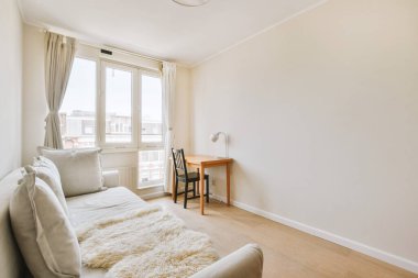 Modern apartmandaki geniş minimalist tarzda oturma odasında halı ve masaya yakın rahat bir kanepe.
