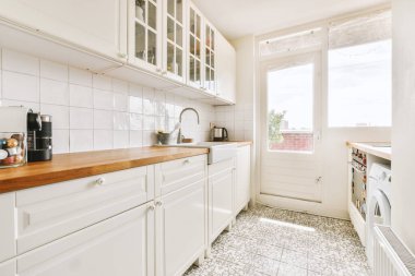 Minimalist tarzı beyaz mobilyalı, lavabolu ve sobalı bir ev mutfağı.