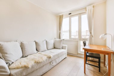 Modern apartmandaki geniş minimalist tarzda oturma odasında halı ve masaya yakın rahat bir kanepe.