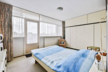 Yatak odasının iç tasarımı, yatak odası ve ahşap gardırop modern dairenin penceresinin kenarına yerleştirilmiş.