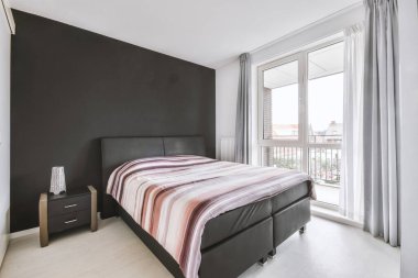 Yatak odasının iç tasarımı, yatak odası ve ahşap gardırop modern dairenin penceresinin kenarına yerleştirilmiş.