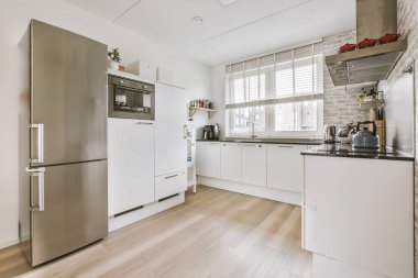 Gündüz vakti çağdaş dairede balkon kapıları olan hafif mutfak ve yemek odasının içi