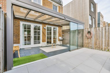 Oturma alanı ve ahşap çitlerin yanındaki küçük bahçesi olan düzgün asfaltlı bir avlu.