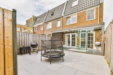 Oturma alanı ve ahşap çitlerin yanındaki küçük bahçesi olan düzgün asfaltlı bir avlu.