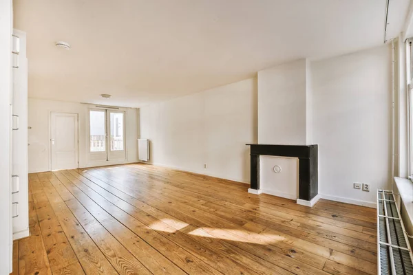 Modern counters with stools placed on wooden floor near electric fireplace in spacious room with white walls