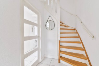 Minimalist iç tasarımı olan modern lüks dairenin ikinci katına çıkan ahşap merdivenli beyaz koridor.