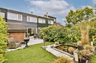 Oturma alanı ve ahşap çitlerin yanındaki küçük bahçesi olan düzgün asfaltlı bir avlu.