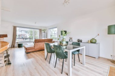 Günümüz minimalist tasarımı. Hafif stüdyo dairesinin ahşap masası ve oturma odası ile beyaz duvarları ve parke zemini arasında yemek masası ve sandalyeleri var.