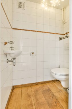 Wall hung toilet and small sink in lavatory room with white tile