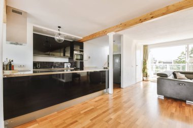 Günümüz minimalist tasarımı. Hafif stüdyo dairesinin ahşap masası ve oturma odası ile beyaz duvarları ve parke zemini arasında yemek masası ve sandalyeleri var.