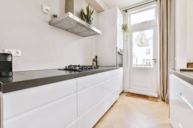 Minimalist tarzı beyaz mobilyalı, lavabolu ve sobalı bir ev mutfağı.