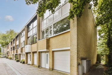 Arabaları, ağaçları ve fenerleri olan boş bir kaldırımdan panorama manzaralı evler.