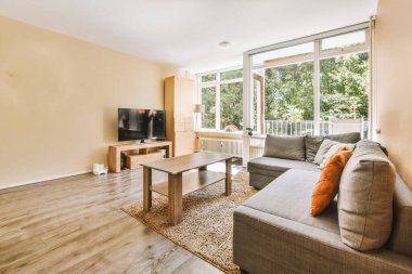 Lambanın altında bulunan sandalye ve çiçeklerle dolu masa modern dairenin geniş odasındaki balkon girişi ve dinlenme odasına karşı.