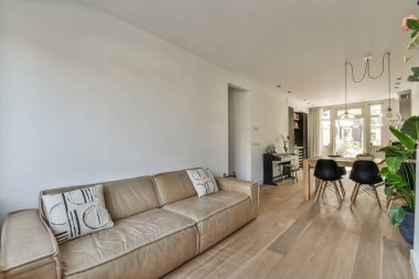 sofa with soft cushions located and electric fireplace in light living room near kitchen