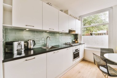 Günümüz minimalist tasarımı. Hafif stüdyo dairesinin ahşap masası ve oturma odası ile beyaz duvarları ve parke zemini arasında yemek masası ve sandalyeleri var.