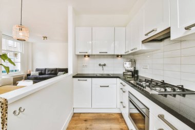 Minimalist tarzı beyaz mobilyalı, lavabolu ve sobalı bir ev mutfağı.