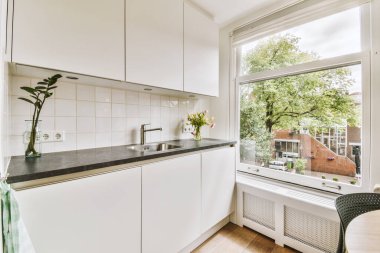 Minimalist tarzı beyaz mobilyalı, lavabolu ve sobalı bir ev mutfağı.