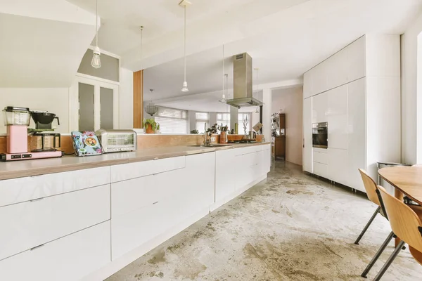 Interior of light kitchen and dining room with balcony doors in contemporary apartment at daytime