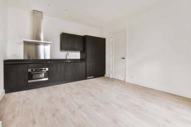 Pencereleri ve ahşap parke zemini olan boş beyaz mutfağın içi.