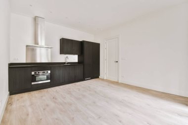 Pencereleri ve ahşap parke zemini olan boş beyaz mutfağın içi.