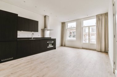 Pencereleri ve ahşap parke zemini olan boş beyaz mutfağın içi.